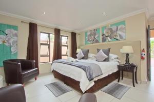1 dormitorio con 1 cama grande y 1 silla en Gecko Inn en Richards Bay