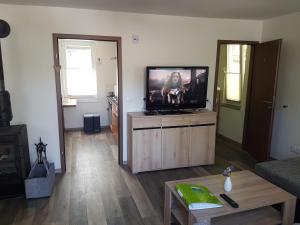 a living room with a flat screen tv on a cabinet at Ferienhaus am Badesee Schönsee Bungalow 12 in Urnshausen +21 photos