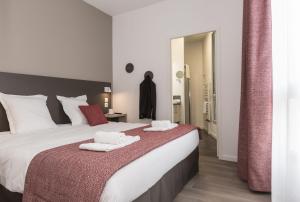 a bedroom with a large bed with towels on it at Odalys City Le Mans Centre Congrès in Le Mans