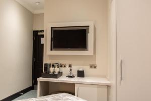 1 dormitorio con TV en la pared y mesa en The Crescent Hyde Park en Londres