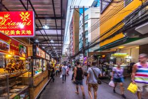 a group of people walking through a street market at Gusto Pratunam Hotel in Bangkok