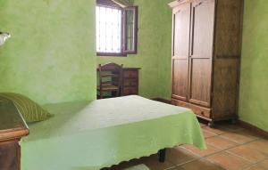 El Algarrobo by CasaTuristica في Algatocín: غرفة نوم خضراء مع سرير وخزانة