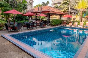 a swimming pool with tables and chairs and umbrellas at Stable Lodge - SHA Certified in Bangkok