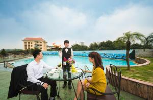 a group of three people sitting around a table in front of a pool at Muong Thanh Grand Phuong Dong in Vinh