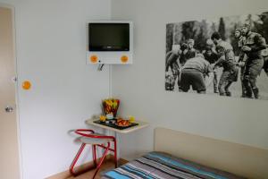 a bedroom with a tv on the wall and a table at Hoteleco Sud Agen Autoroute in Le Passage