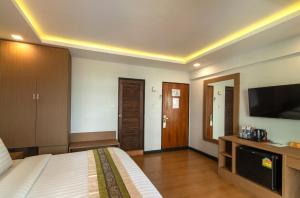 a hotel room with a bed and a flat screen tv at Stable Lodge - SHA Certified in Bangkok