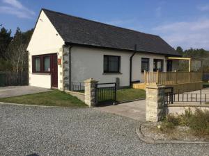 uma casa branca com um alpendre e um deque em Lesanne Cottage em Inverness