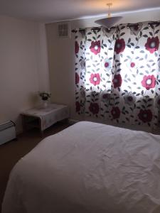 ロジーマスにある2 bedroom flat near the beachのベッドルーム1室(花のカーテン付きの大型ベッド1台付)