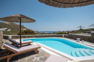 a swimming pool with a chair and an umbrella at Happy Villas Mykonos in Kalafatis