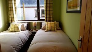 two beds in a room with a window at Lesanne Cottage in Inverness