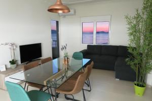 een woonkamer met een glazen tafel en stoelen bij On the Beach (literally) stylish apartment with free P in Vlorë