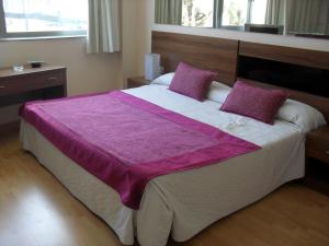 a bedroom with a large bed with purple sheets and pillows at Hotel El Cruce in Moraleda de Zafayona