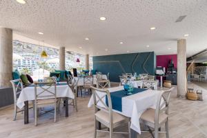 a dining room with white tables and chairs at Holiday Club Puerto Calma in Puerto Rico de Gran Canaria