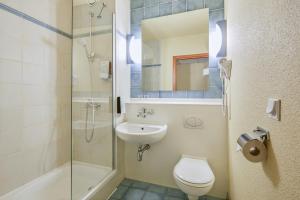 a bathroom with a toilet and a sink and a shower at Campanile Hotel Szczecin in Szczecin