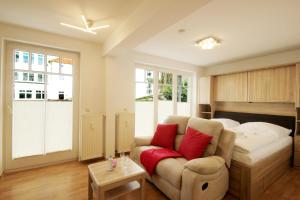 1 dormitorio con 1 cama y 1 sofá con almohadas rojas en Haus Jahreszeiten by Rujana, en Binz
