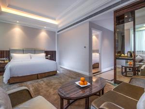 a hotel room with a bed and a living room at Vienna International Hotel Guangdong Puning Sqaure in Puning