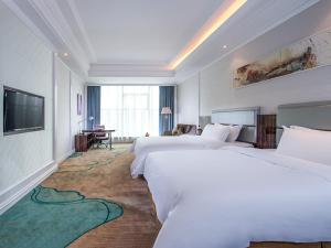 um quarto de hotel com duas camas e uma televisão em Vienna International Hotel Guangdong Puning Sqaure em Puning