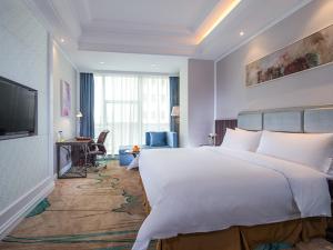 a hotel room with a large bed and a desk at Vienna International Hotel Guangdong Puning Sqaure in Puning