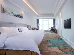um quarto de hotel com uma cama grande e uma televisão em Vienna International Hotel Guangdong Puning Sqaure em Puning