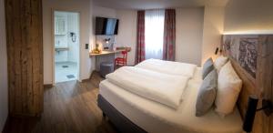 a hotel room with a bed with white pillows at Hotel & Brauerei-Gasthof Neuwirt in Neuburg an der Donau