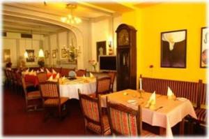 ein Restaurant mit Tischen, Stühlen und einer Uhr in der Unterkunft Hotel Restaurant Itzumer Paß in Hildesheim