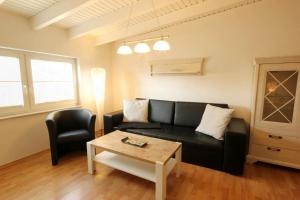 a living room with a black couch and a table at Haus Jahreszeiten by Rujana in Binz