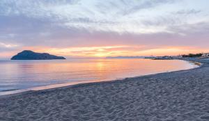 a view of a beach with a sunset in the background at Porto Platanias Beach Luxury Selection - Adults Only in Plataniás