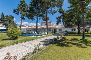 an exterior view of a house with a swimming pool and trees at Villa Maia in Corroios