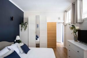 um quarto com uma cama branca e uma televisão em Elégant appartement en plein coeur de Cabourg - Les locations de Proust em Cabourg