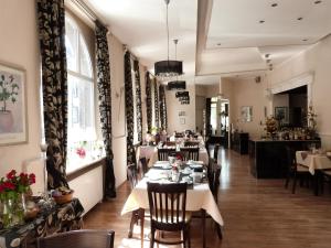 a dining room with tables and chairs and windows at Hotel Jägerhof in Mayen