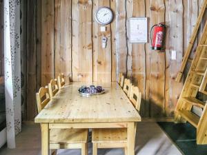 a wooden table with chairs and a clock on a wall at Holiday Home Vuokatinportti b 9 by Interhome in Lahdenperä
