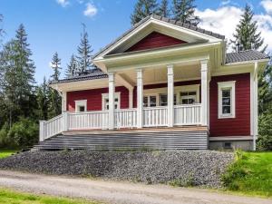 una casa roja con un porche blanco en la entrada en Holiday Home Villa urho by Interhome en Löytö