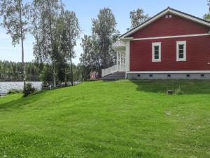 a red house on a grassy hill next to a lake at Holiday Home Villa elisabet by Interhome in Löytö