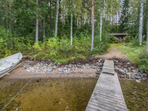 a wooden bridge over a river with a boat at Holiday Home Länsiranta by Interhome in Hirvikoski