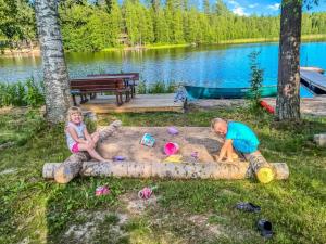 duas crianças a brincar num poço de areia junto a um lago em Holiday Home Villa urho by Interhome em Löytö