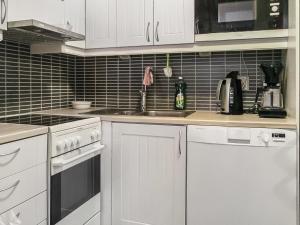 eine weiße Küche mit weißen Geräten und schwarzen Fliesen in der Unterkunft Holiday Home Vuokatinportti b 9 by Interhome in Lahdenperä