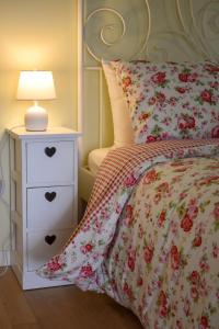 1 cama con colcha de flores y mesita de noche con lámpara en B&B Villa Elisa, en Motta di Livenza