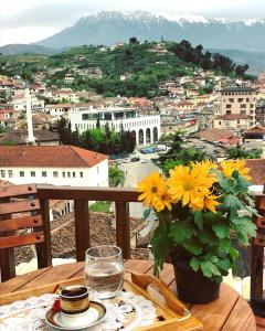 een tafel met een vaas met gele bloemen op een balkon bij Guesthouse Arjan in Berat