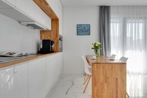 a kitchen with white cabinets and a wooden counter top at GRANO FLATS Gdańsk - Apartament Nadmorze in Gdańsk