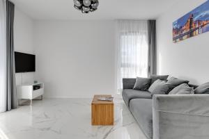 a white living room with a couch and a tv at GRANO FLATS Gdańsk - Apartament Nadmorze in Gdańsk