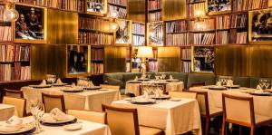 a restaurant with tables and chairs and books at Preciados in Madrid