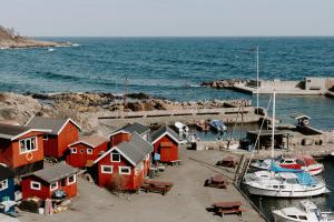 eine Gruppe roter Häuser und eine Anlegestelle mit einem Boot in der Unterkunft Hotel Sandvig Havn in Allinge