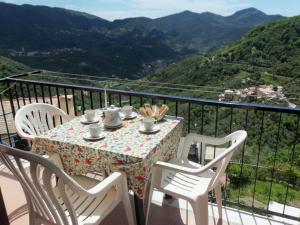 a table with a tea set on a balcony with mountains at Luna Rossa da Nadia in Levanto