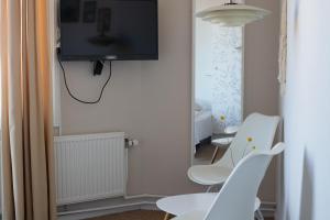 アリンエにあるHotel Sandvig Havnの壁にテレビと椅子2脚が備わる客室です。