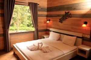 Safari Resort في بونشاك: غرفة نوم مع اثنين من مناشف البجع على سرير