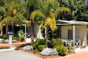 a house with a palm tree in front of it at Acclaim Kingsway Tourist Park in Perth