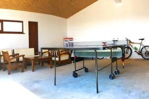 a ping pong table in a room with chairs and a bike at Guest House Arima in Sushina