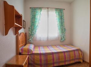 een kleine slaapkamer met een bed en een raam bij Große Sonnenterrasse, 200 Meter zum Strand... in Santa Pola