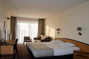 ein Hotelzimmer mit einem großen Bett und einem Stuhl in der Unterkunft Hotel Arcato in De Haan