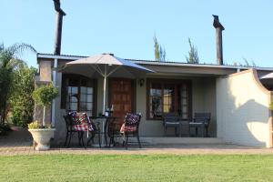 una casa con mesa, sillas y sombrilla en Drakensview Self Catering en Winterton